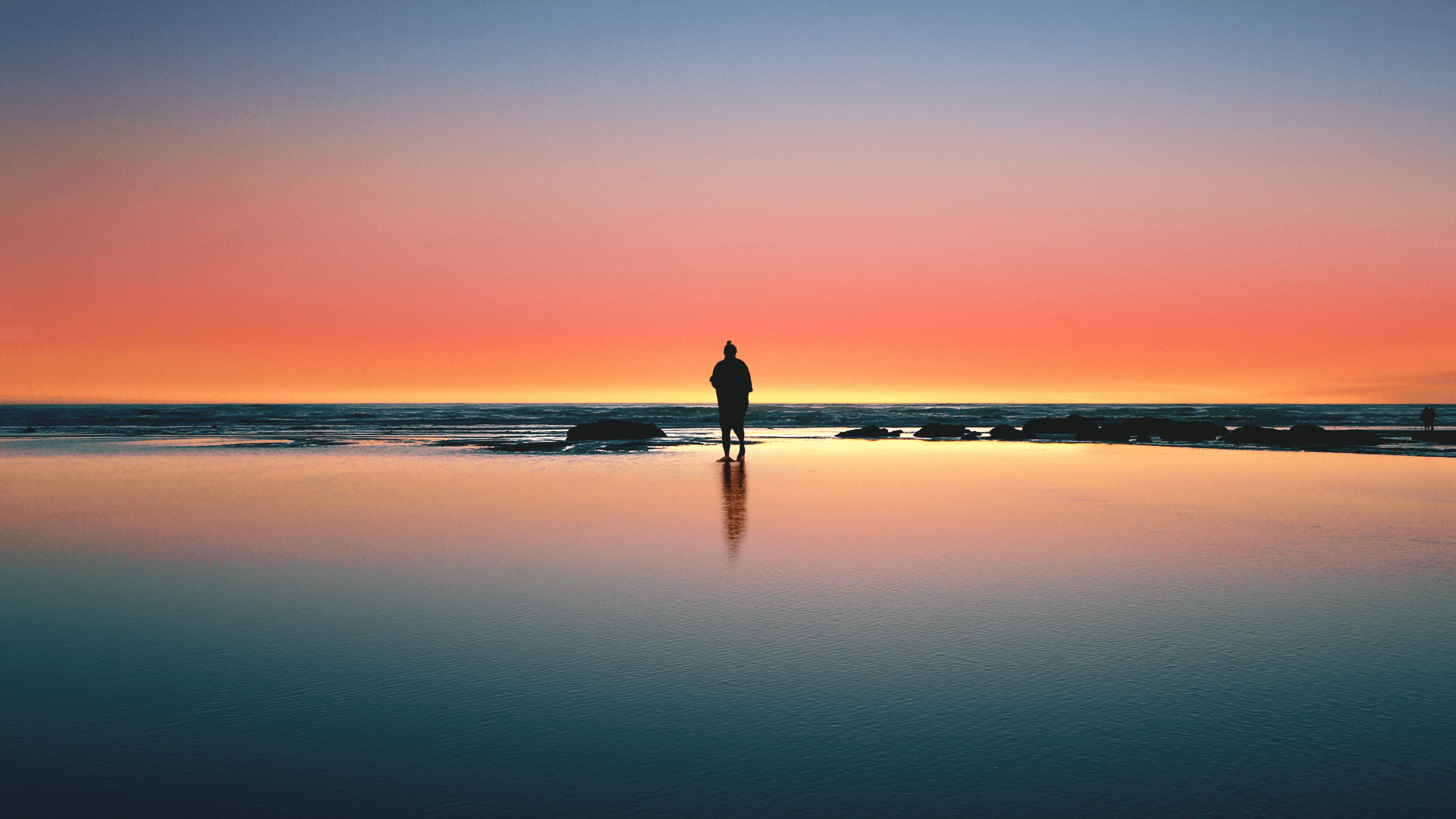 Couple silhouetted on the beach at sunset