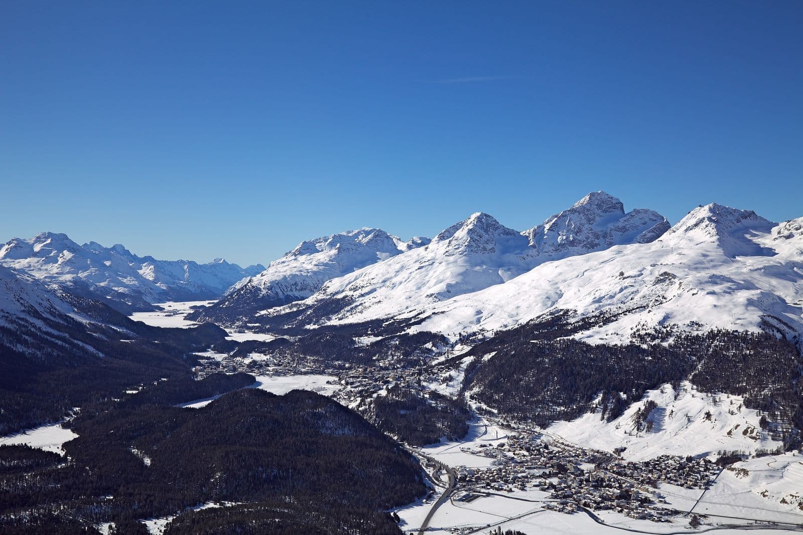 Panoramic view over a snowy alpine valley from a summit