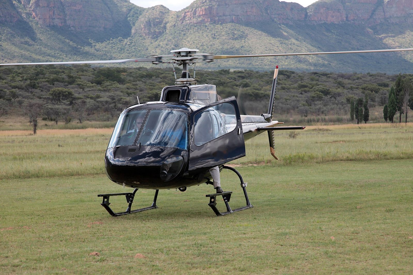 Private helicopter waiting on a grassy landing pad
