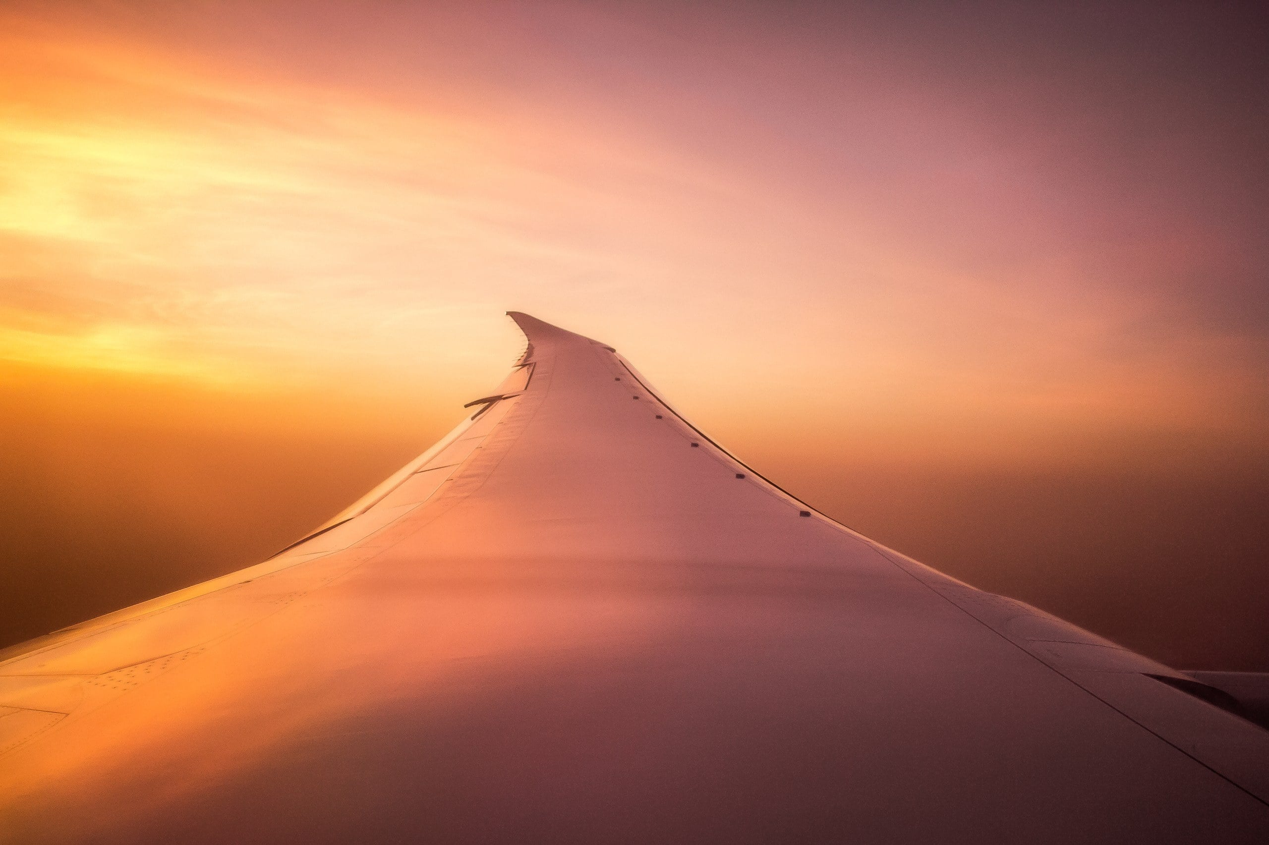 Aircraft wing above the clouds at sunset