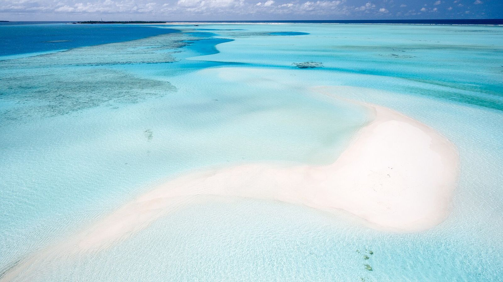 Aerial view of a tiny sandbank in a turquoise lagoon