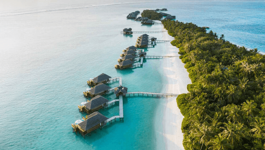 Overwater villas along a palm-covered island, seen from the air