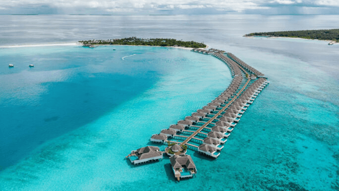 Long arc of overwater villas across a pale lagoon
