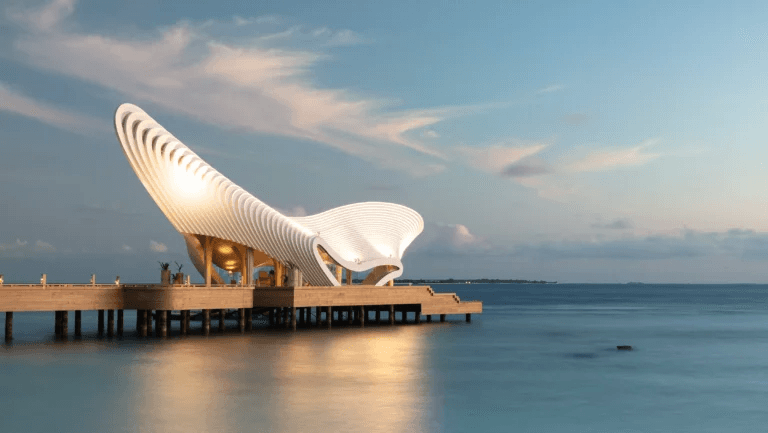 Sculptural white pavilion on a jetty over the sea at dusk