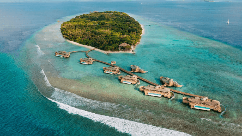 Forested island with overwater villas reaching into the lagoon