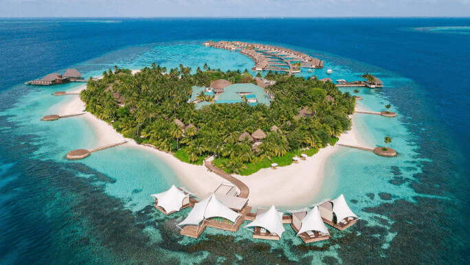 Forested island with white beach pavilions and overwater villas