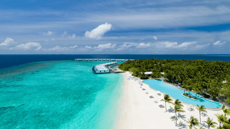 Island beach and lagoon pool beside turquoise water, seen from the air