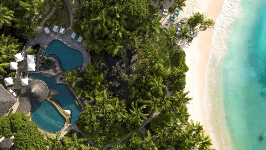 Pools and gardens beside a white beach, seen from directly above