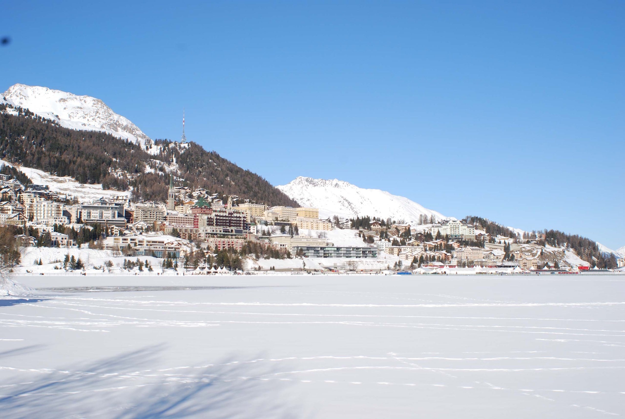 St. Moritz and its snowy mountains seen across the frozen lake