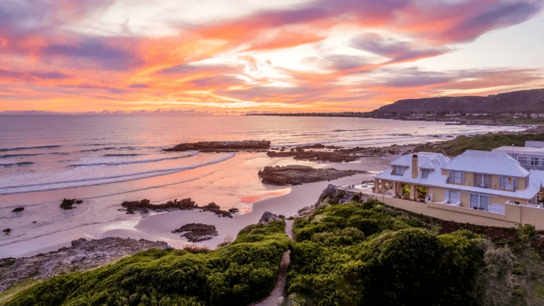 Clifftop house above a rocky shore at sunset