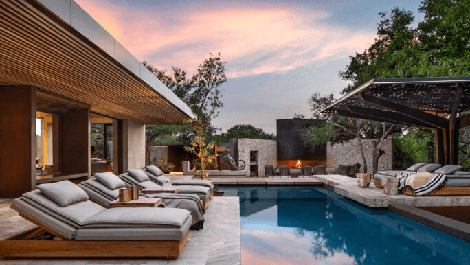 Modern lodge deck with loungers beside a pool at dusk