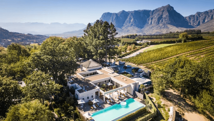 Estate lodges and pool among rolling farmland below mountains