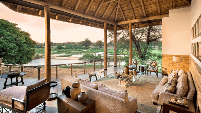 Thatched lodge lounge open to a river view