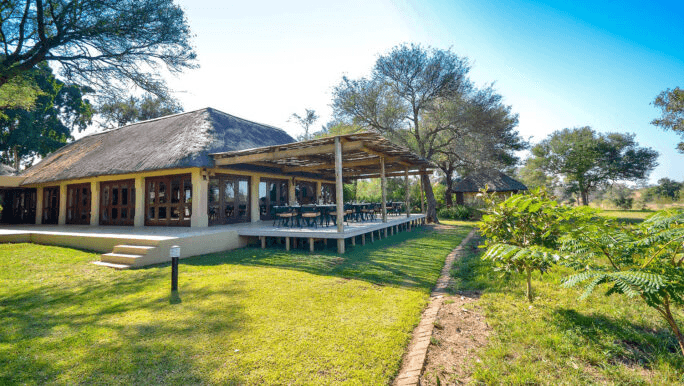 Thatched lodge veranda beside a lawn and trees
