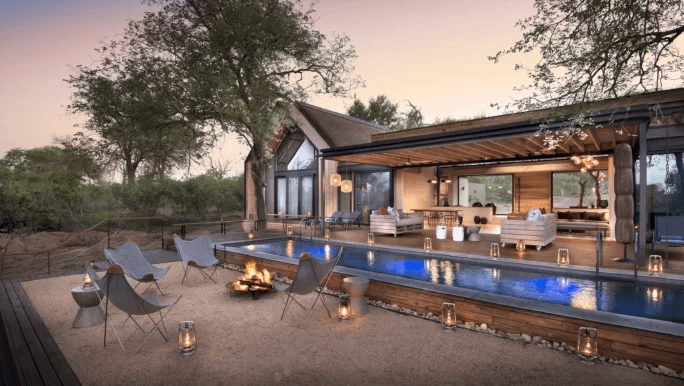 Lodge deck with a fire pit and pool at dusk