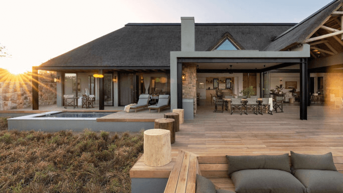 Thatched lodge with a deck and plunge pool at sunset