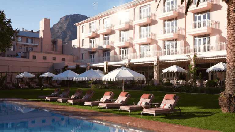 Pink colonial hotel beside a pool, with Table Mountain behind