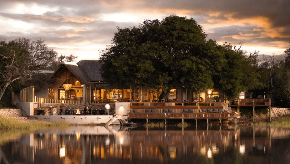Lodge reflected in a waterhole at sunset