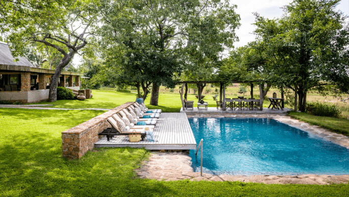 Pool and lawn in front of a farmhouse-style lodge