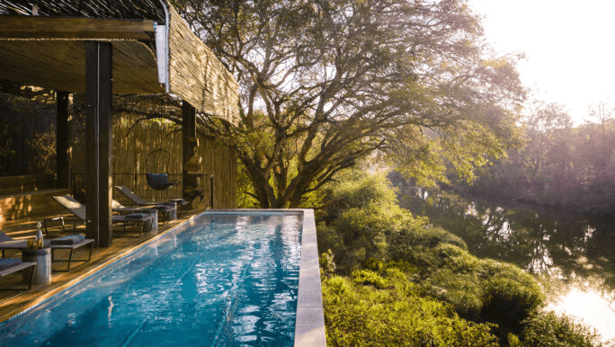 Plunge pool on a deck facing a river at dusk