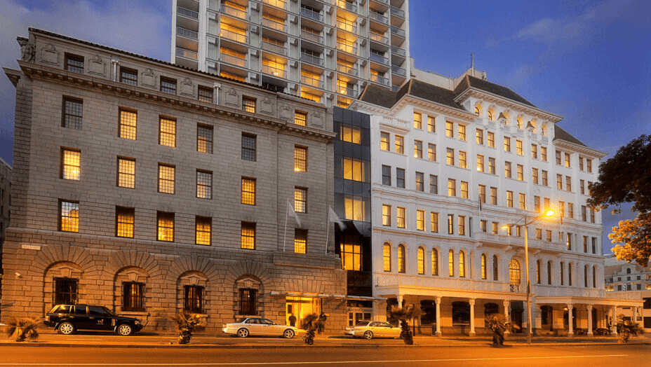 Historic stone building and modern tower lit at dusk