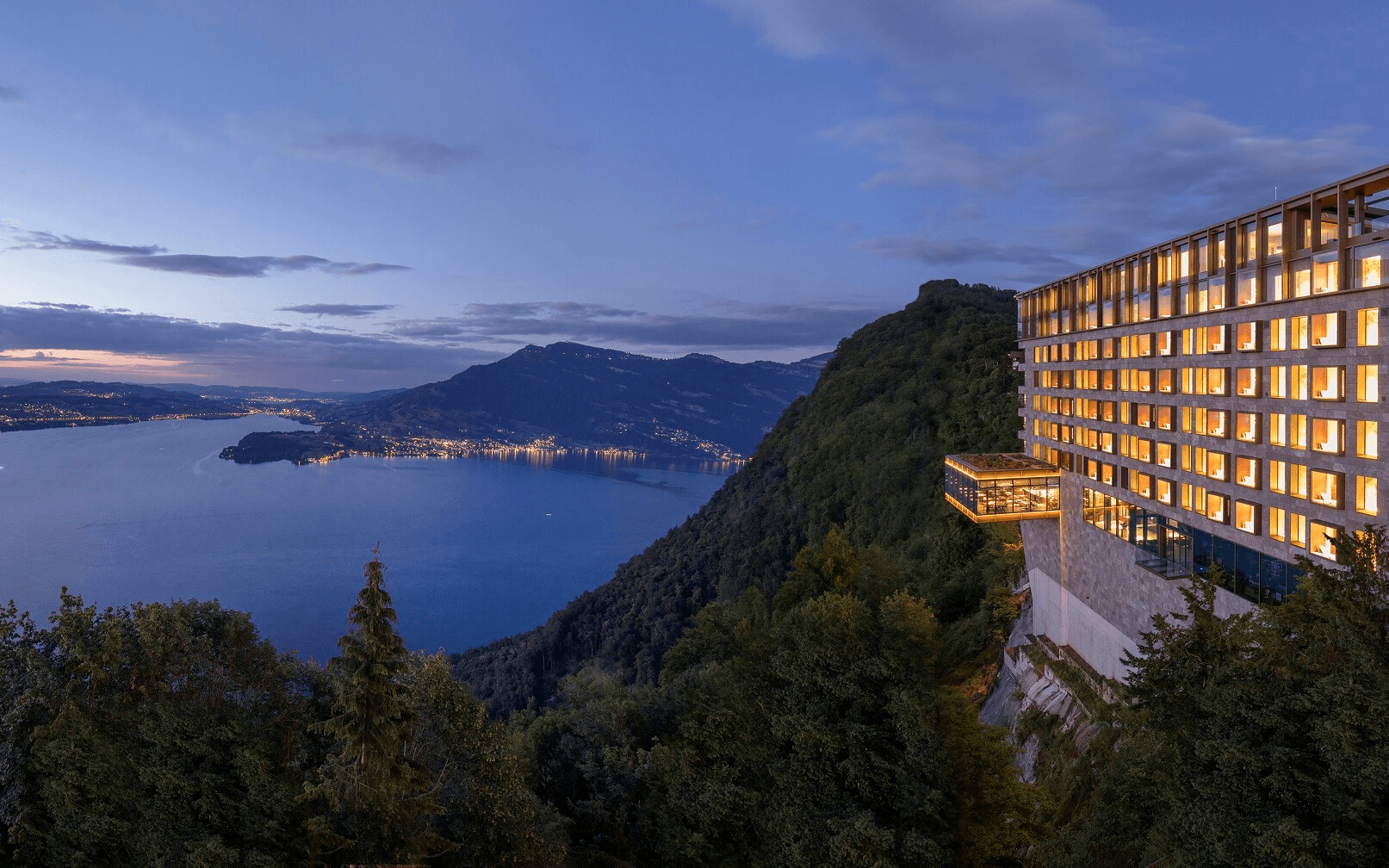 Clifftop hotel overlooking a lake at dusk