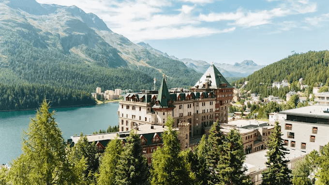 Turreted palace hotel above a lake in a green alpine valley