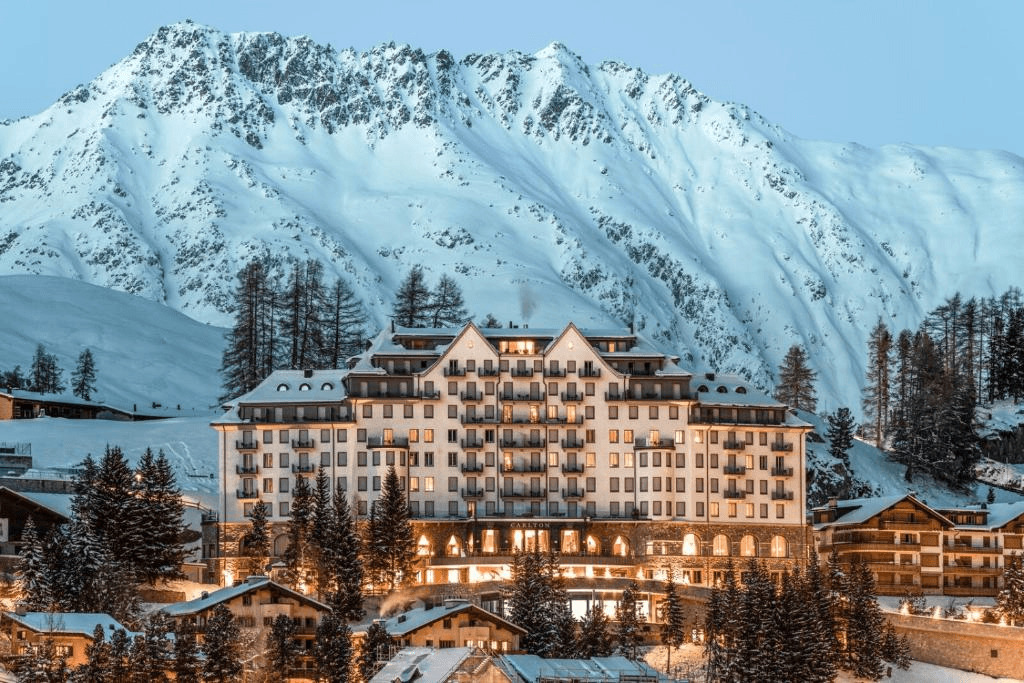 Grand hotel lit up below snowy mountains