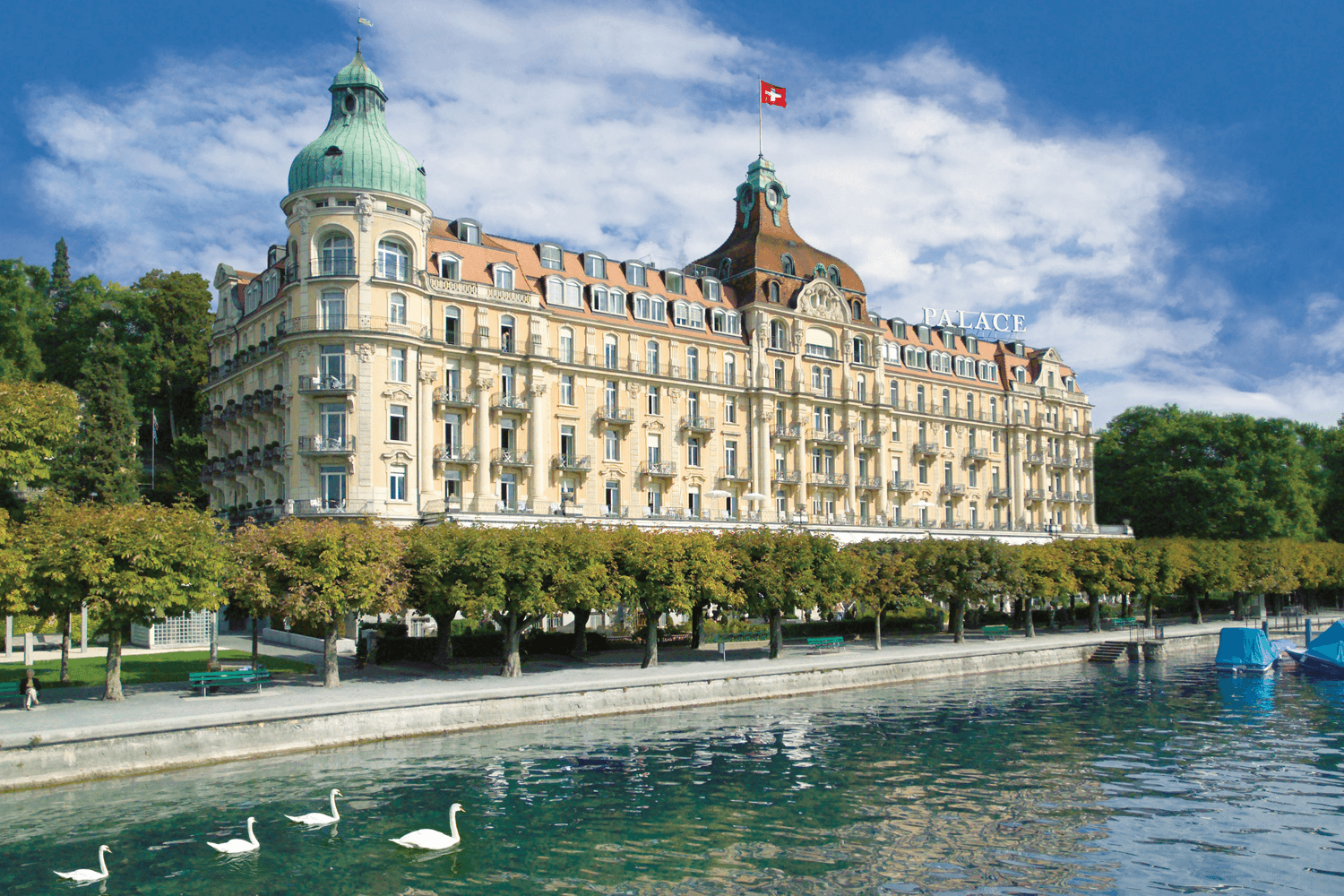 Domed palace hotel on a lakeside promenade with swans
