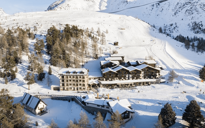 Mountain hotel on a snowy plateau among larches