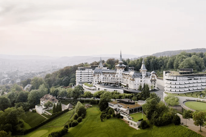 Turreted grand hotel above the city, seen from the air