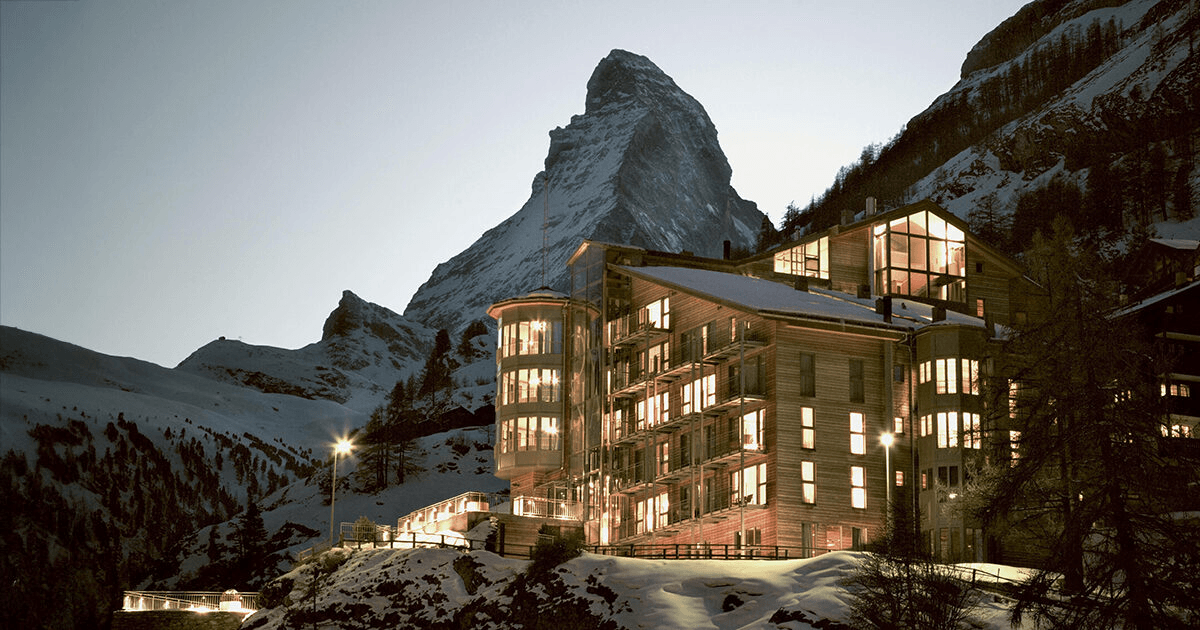 Modern mountain hotel lit at dusk below the Matterhorn
