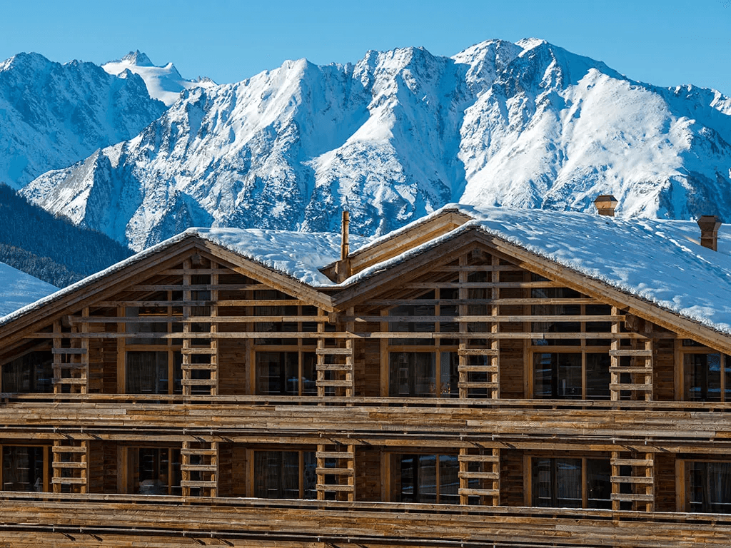 Timber chalet facade below snowy peaks