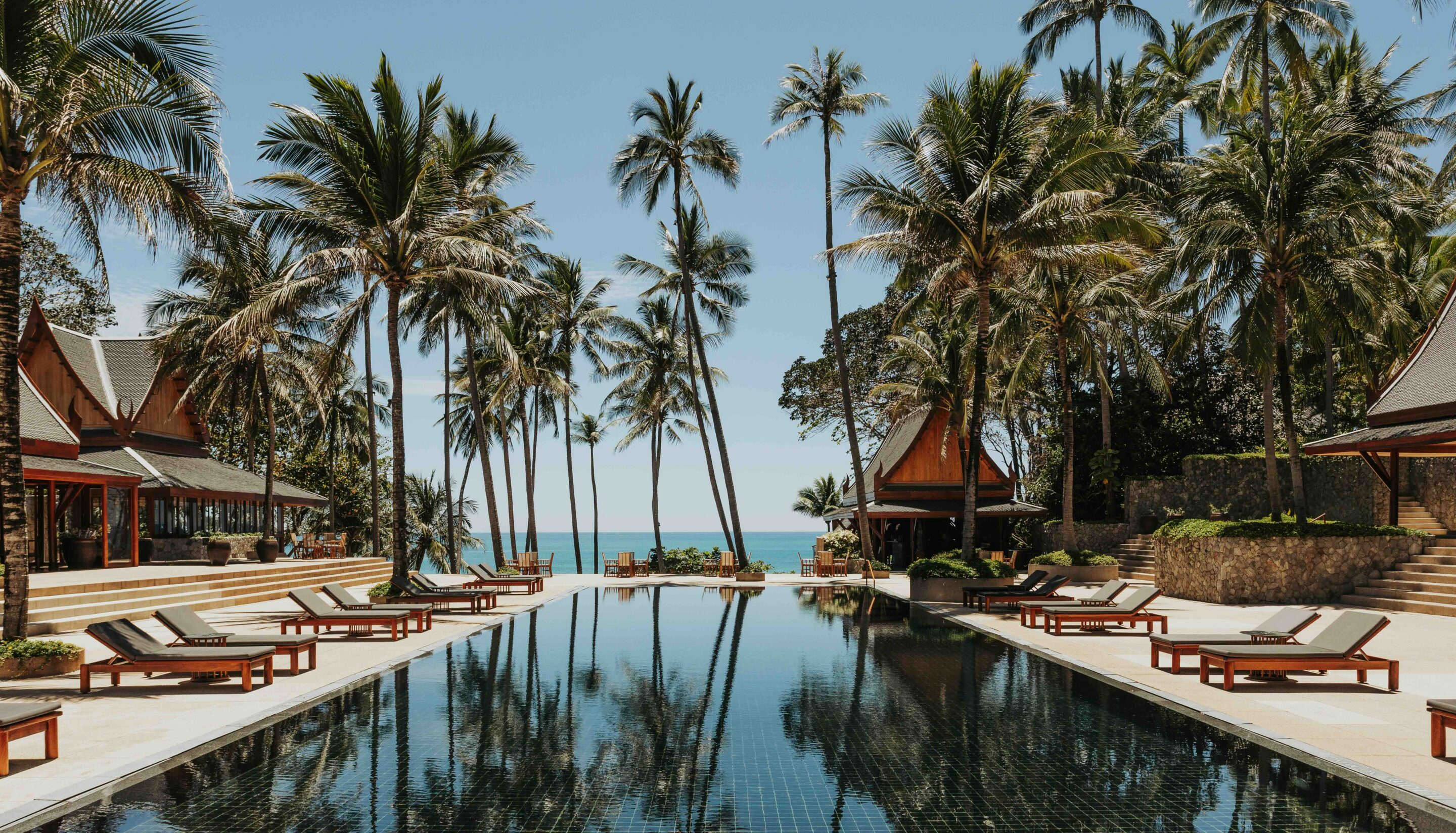 Long pool between palms and Thai pavilions above the sea