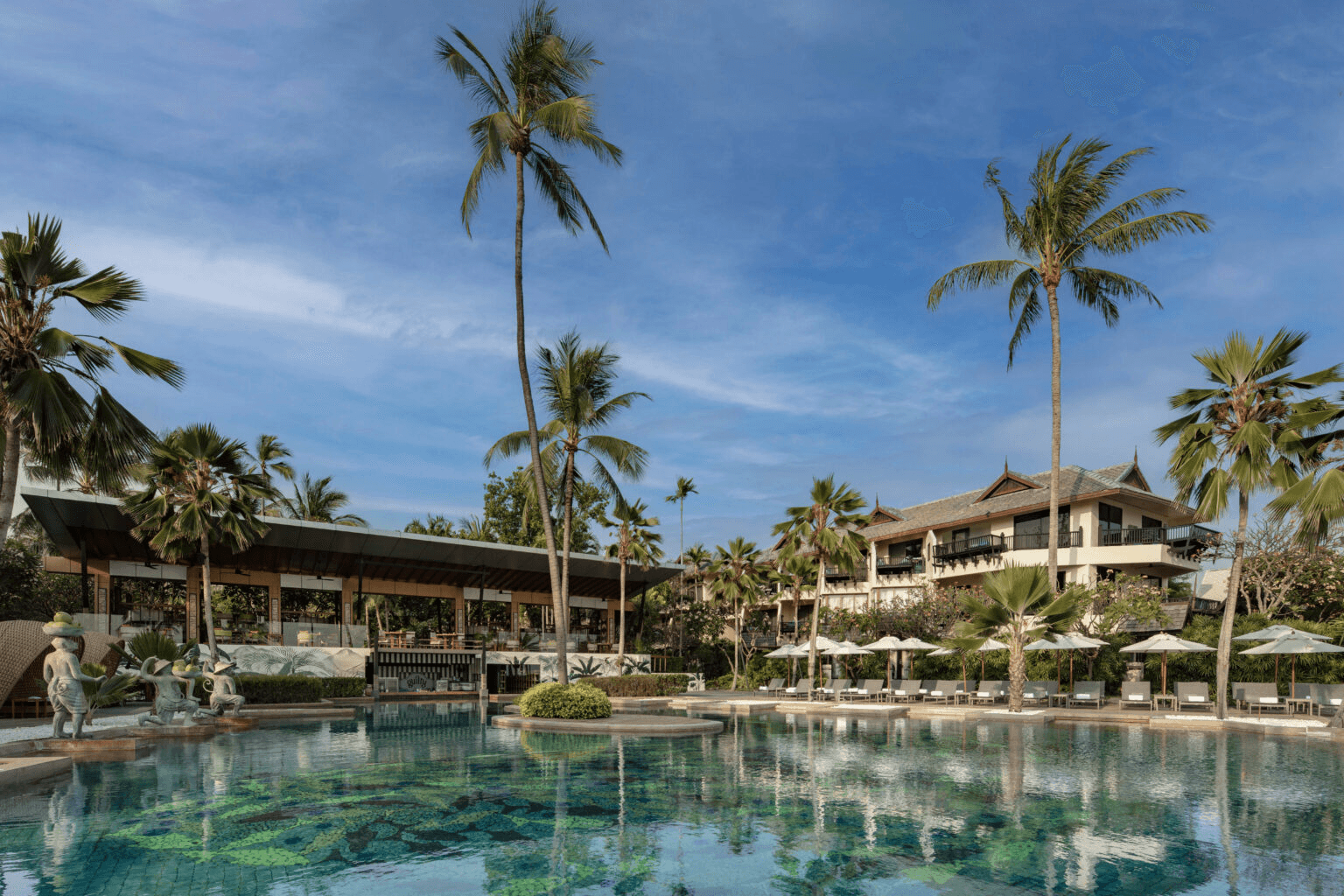 Palm-lined pool in front of the resort buildings