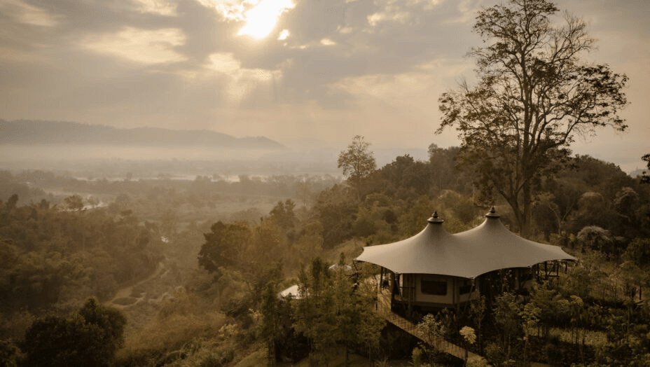 Tented pavilion on a forested hilltop in morning haze