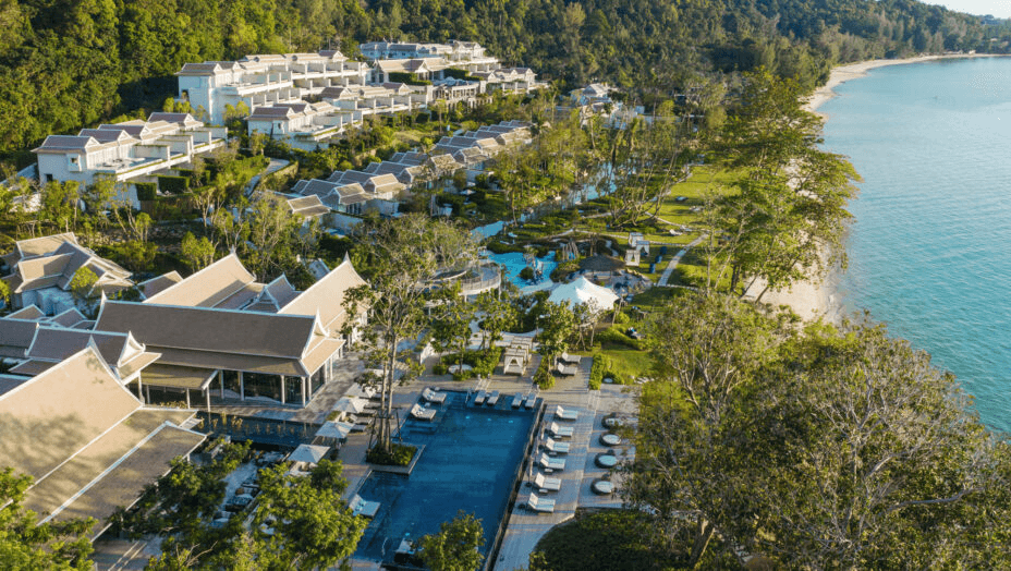Hillside villas and pools above a sandy bay, seen from the air