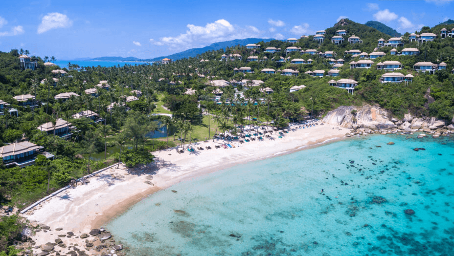 Hillside villas above a turquoise bay, seen from the air