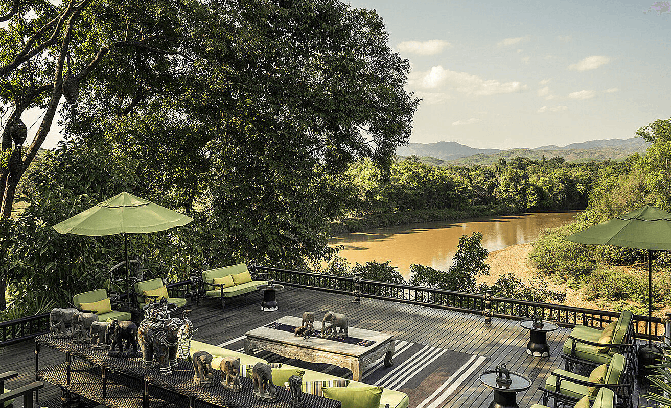 Deck with tables and parasols above a jungle river