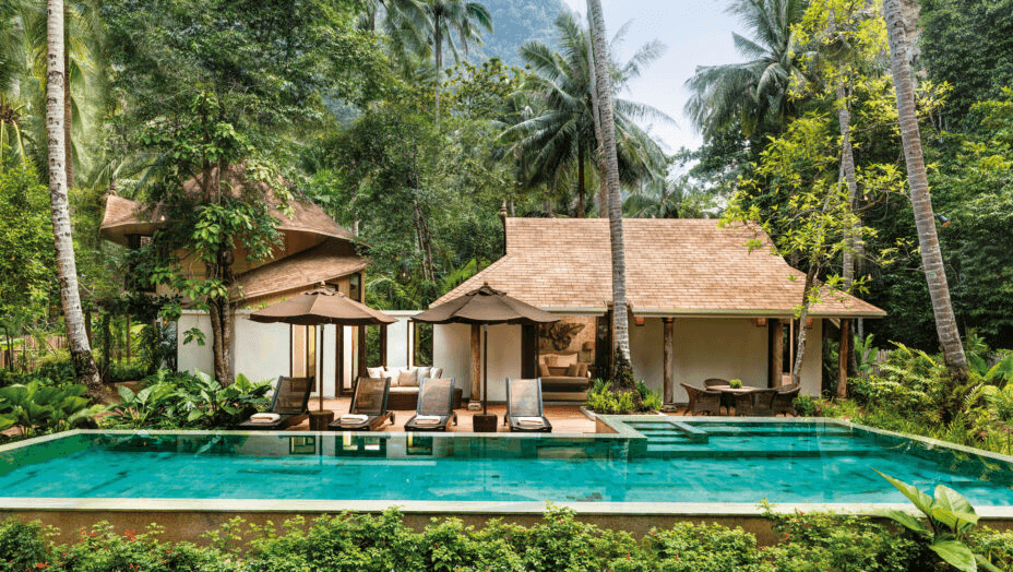 Thatched pavilions beside a pool under palm trees