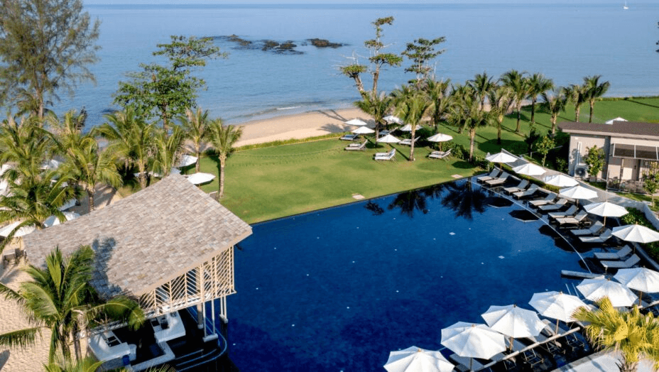 Pool, lawn and loungers beside a sandy beach