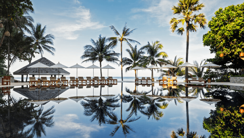 Palms and a beach pavilion reflected in a pool