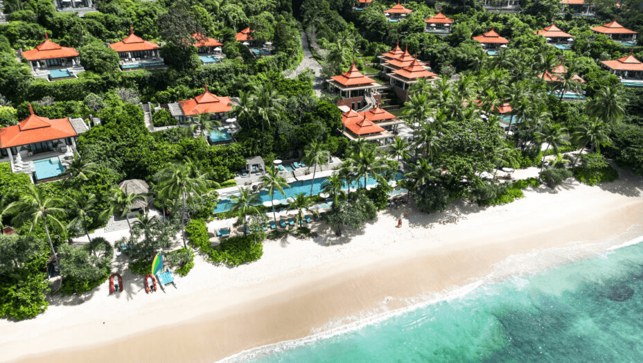 Villas with orange roofs above a white beach, seen from the air