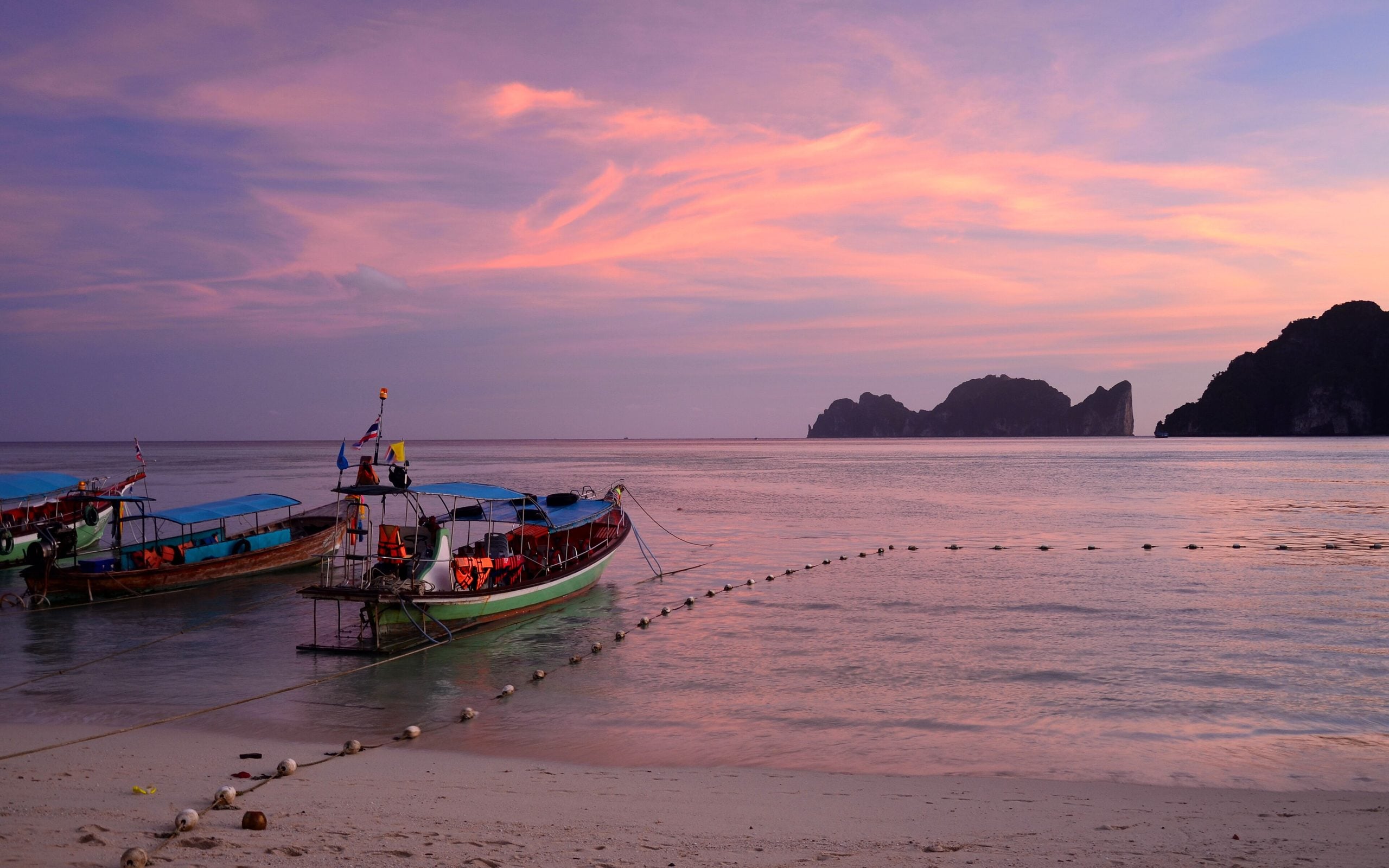 Longtail boats at dusk beneath limestone islands