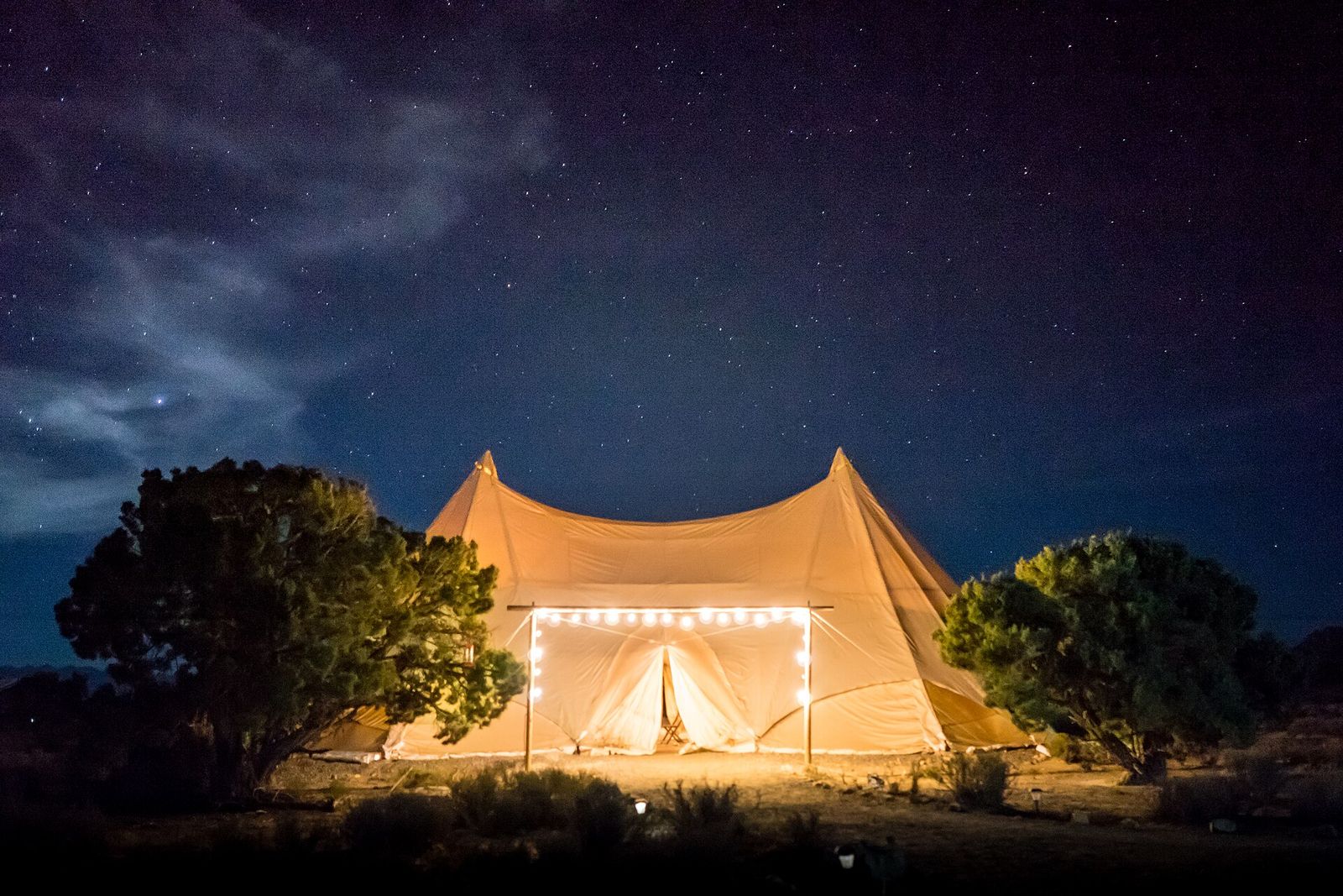 Glowing tent at a desert camp under the night sky