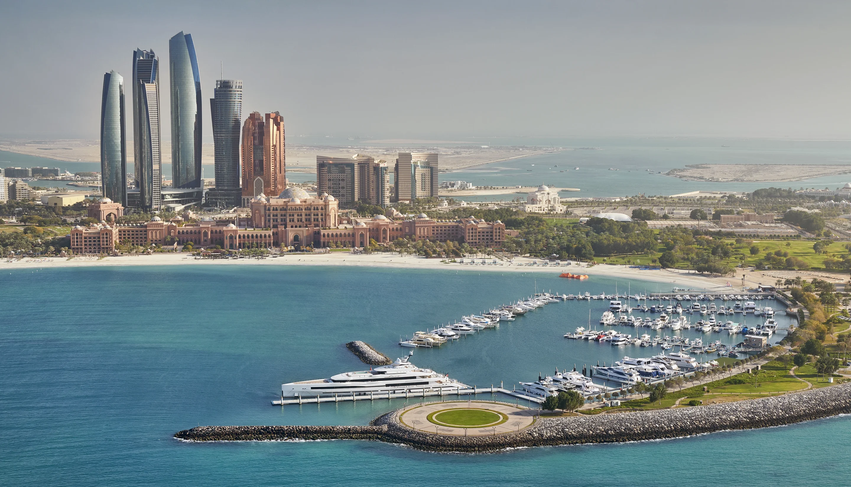Emirates Palace and its marina with the Abu Dhabi skyline behind, seen from the air