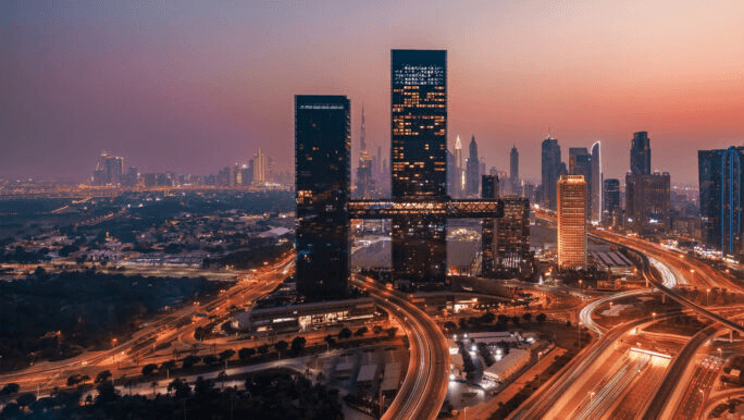 Twin towers joined by a sky bridge above the city at dusk