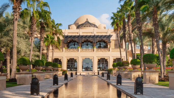 Domed palace and a lantern-lined reflecting pool between palms