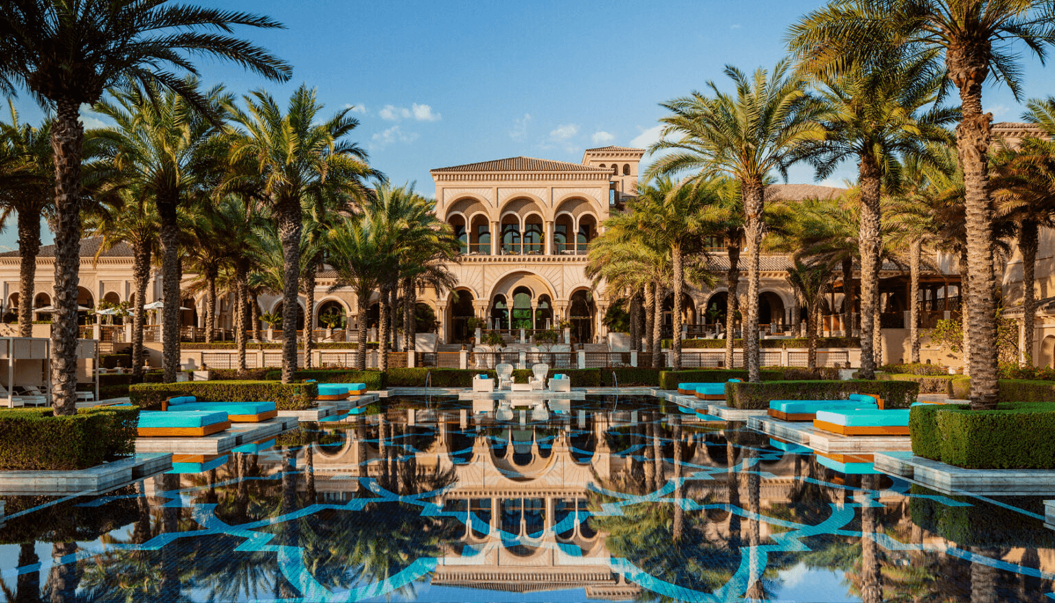 Moorish-style mansion reflected in a palm-lined pool