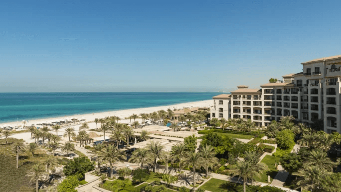 Resort buildings and gardens above a long white beach
